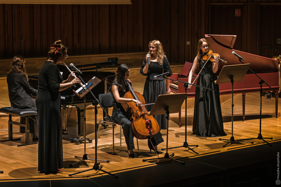 Na zdjęciu pięć dziewcząt z instrumentami muzycznymi na scenie