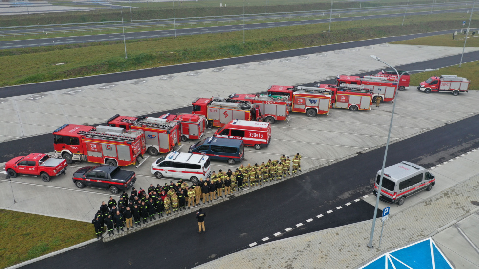 Na zdjęciu stojący ludzie 