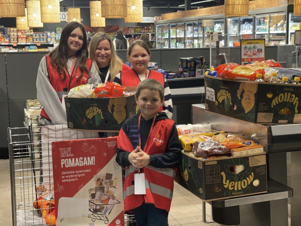 Na zdjęciu stojący ludzie 