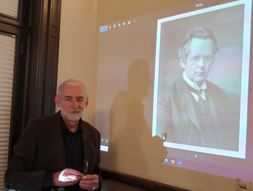 Na zdjęciu mężczyzna, a w tle wyświetlana prezentacja