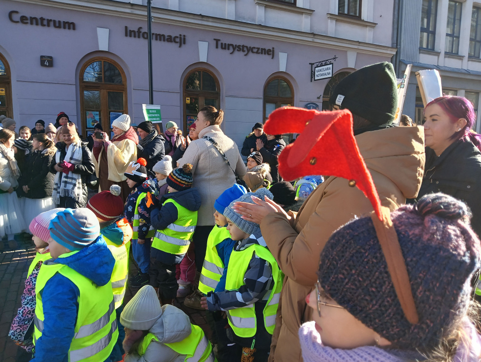 Na zdjęciu stojący ludzie 