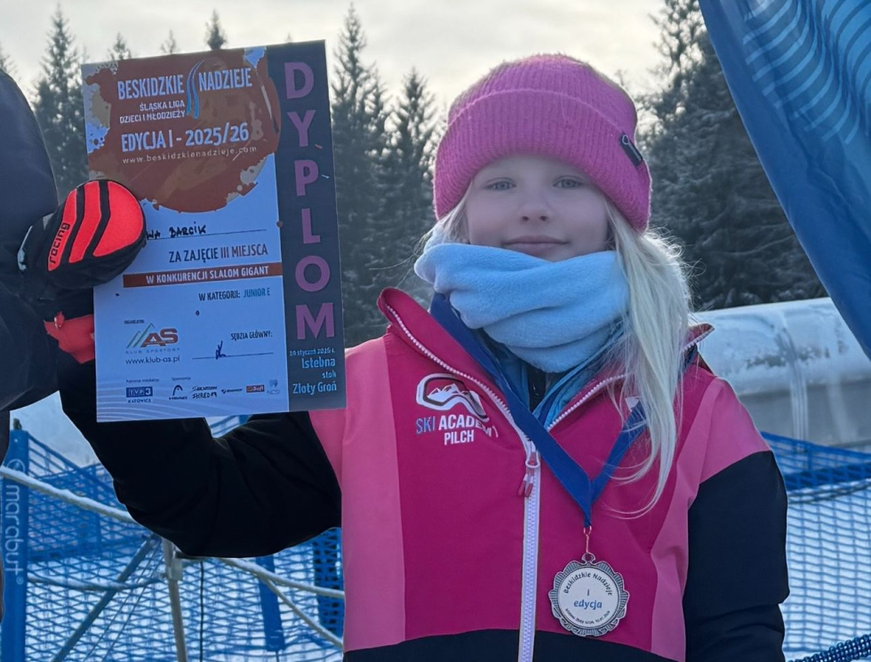 Na zdjęciu dziewczynka z dyplomem i medalem na szyji