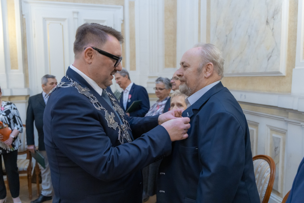 Na zdjęciu stojący ludzie 