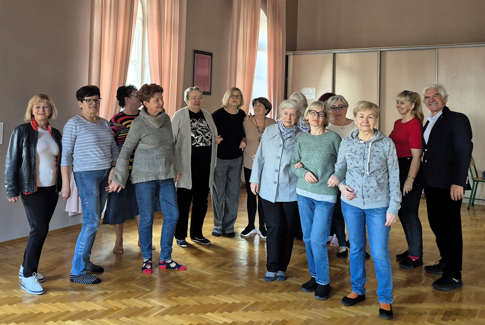 Na zdjęciu stojący ludzie 