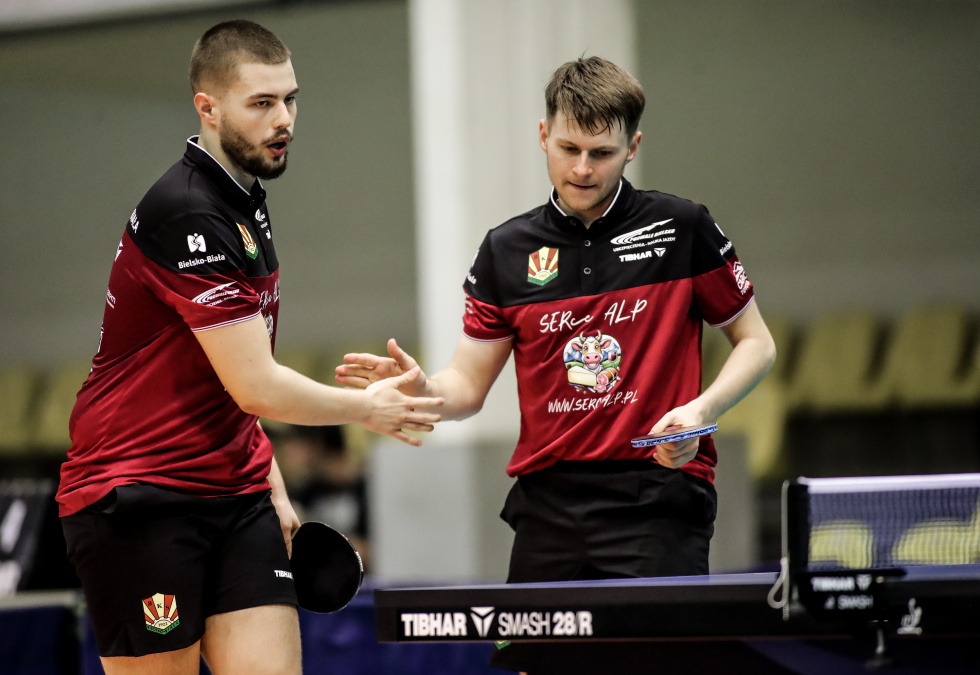 Na zdjęciu stojący ludzie 