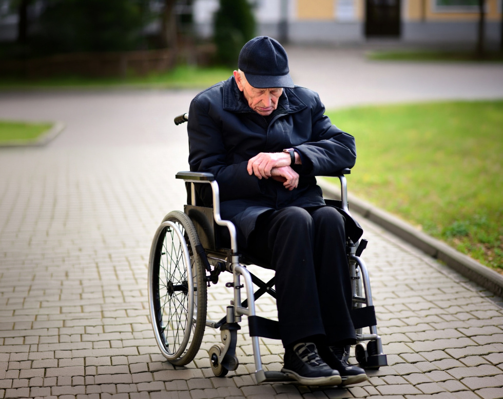 Na zdjęciu straszy człowiek na wózku inwalidzkim 
