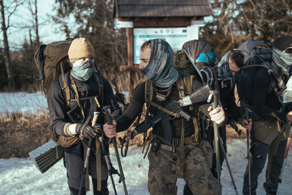 Na zdjęciu stojący ludzie 