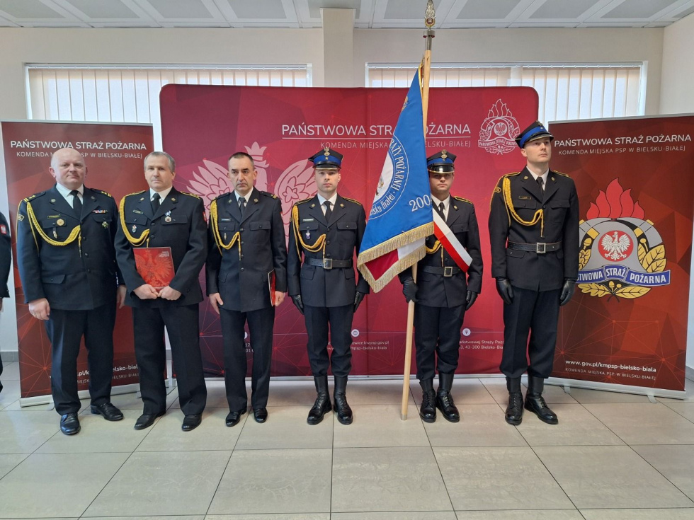 Na zdjęciu stojący ludzie 