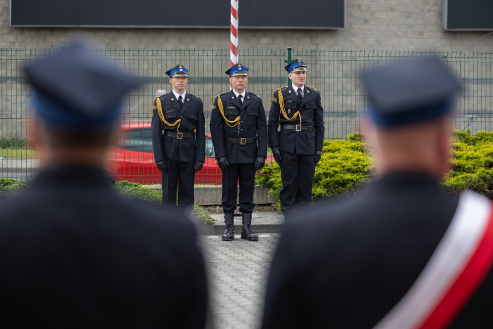 Na zdjęciu stojący ludzie 
