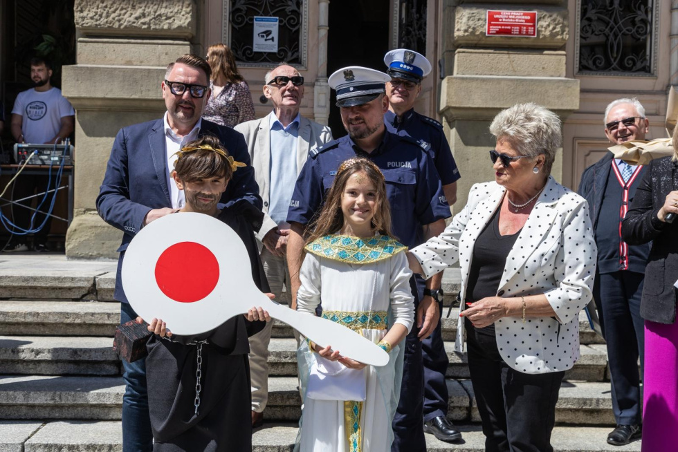 Na zdjęciu stojący ludzie 