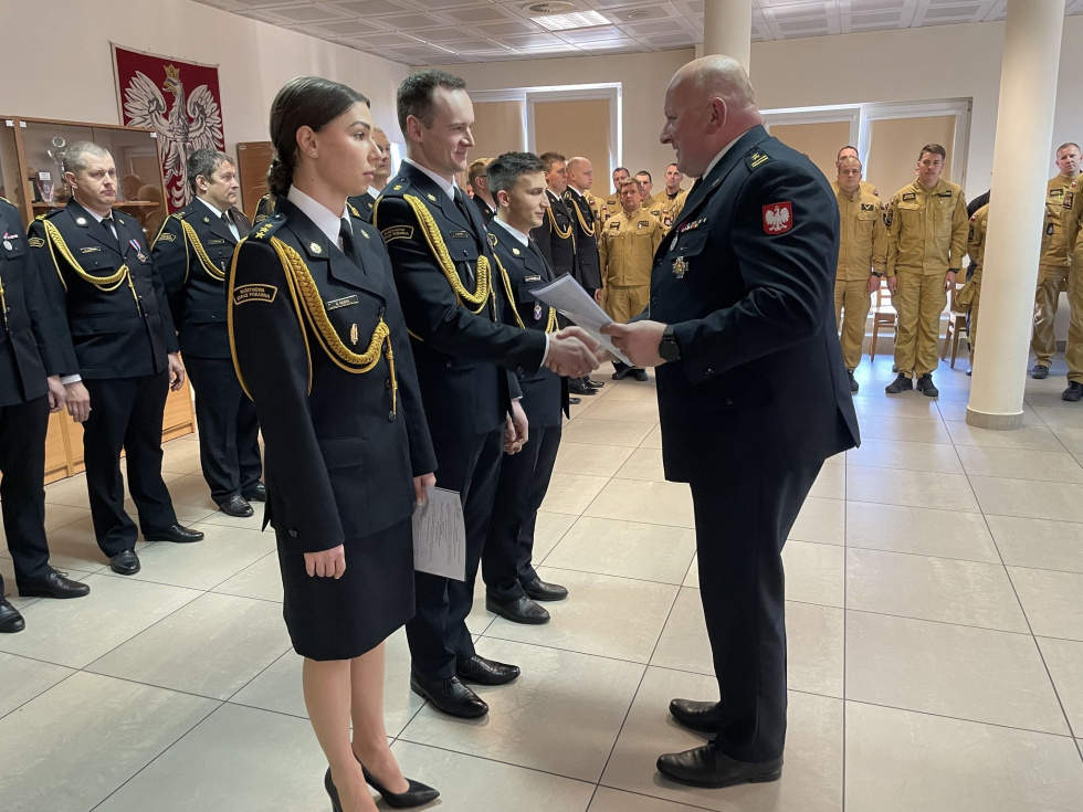 Na zdjęciu stojący ludzie 