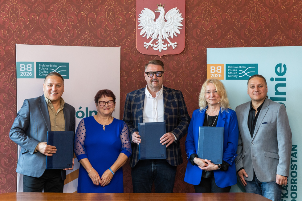 Na zdjęciu stojący ludzie 