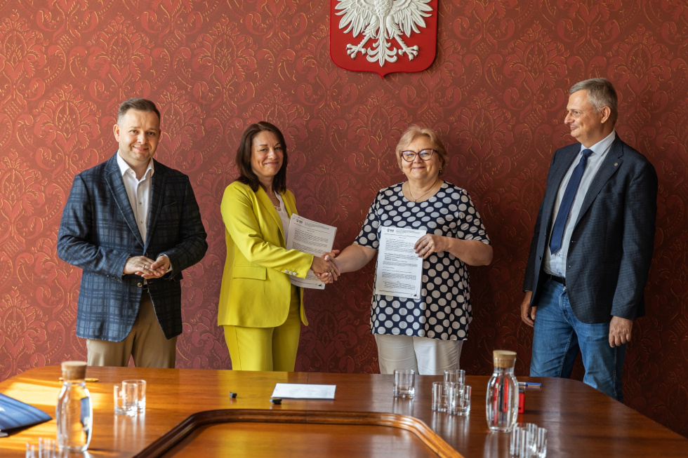 Na zdjęciu stojący ludzie 