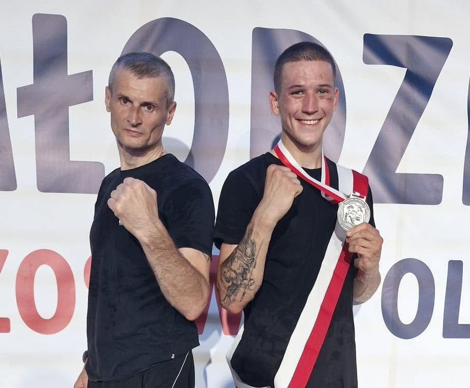 Na zdjęciu stojący ludzie 