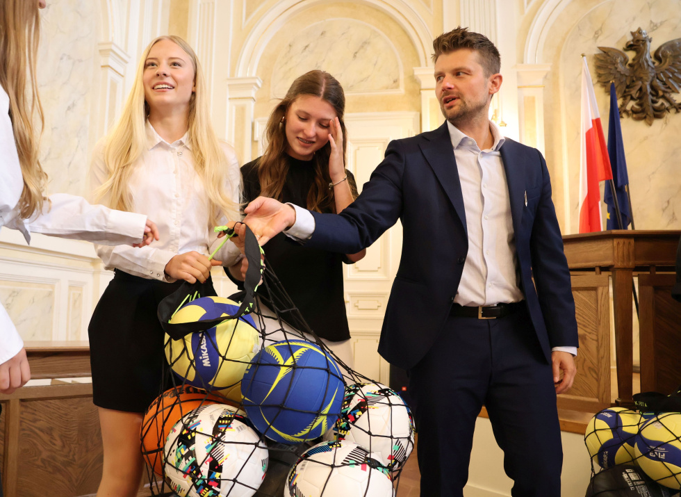 Na zdjęciu stojący ludzie 