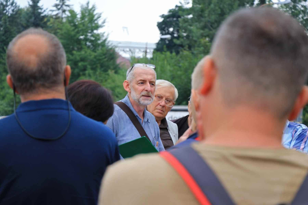 Na zdjęciu stojący ludzie 