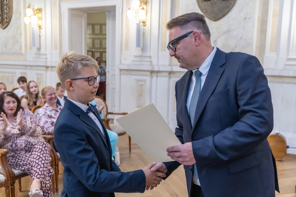Na zdjęciu prezydent wręcza stypendium uczniowi podstawówki 