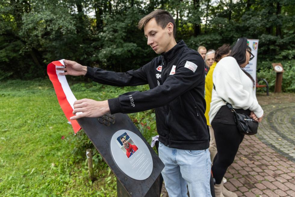 Na zdjęciu stojący ludzie 