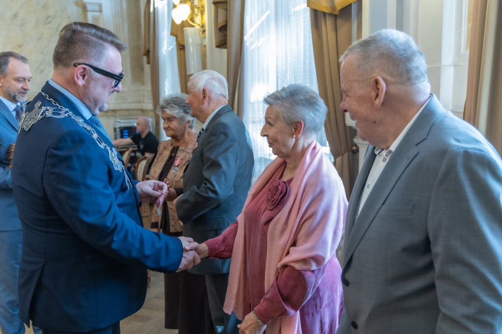 Na zdjęciu stojący ludzie 
