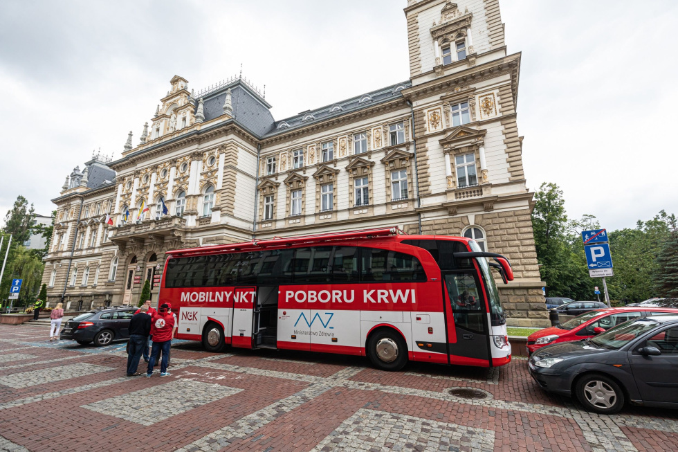 Na zdjęciu biało-czerwony ambulans przed historycznym budynkiem
