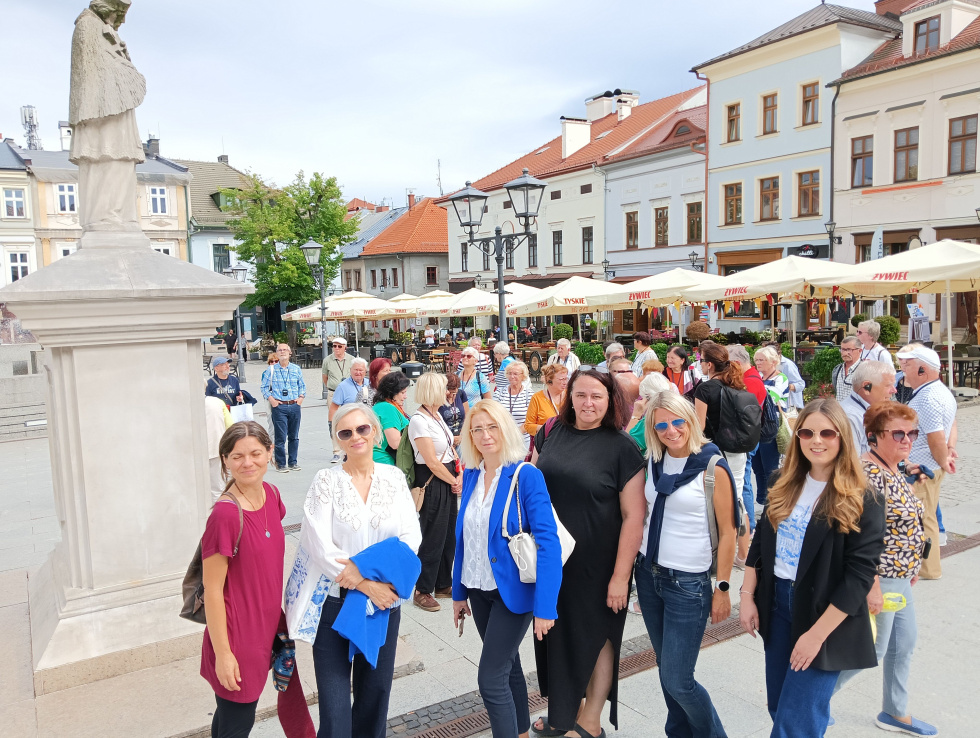 Na zdjęciu stojący ludzie 