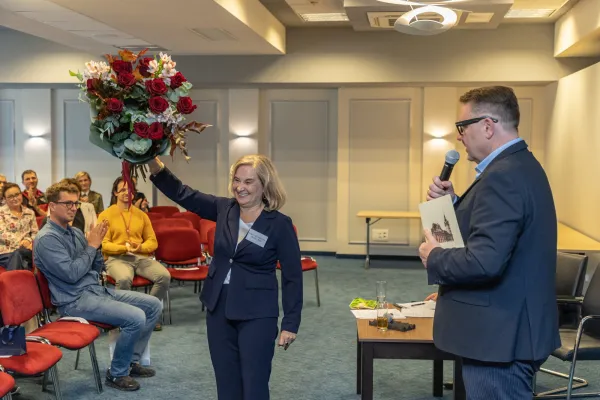 Na zdjęciu stojący ludzie 