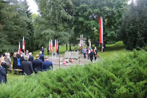 Na zdjęciu stojący ludzie 