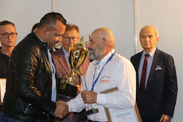 Na zdjęciu stojący ludzie 