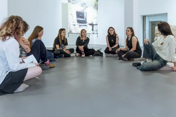 Na zdjęciu osoby siedzące na podłodze w galerii