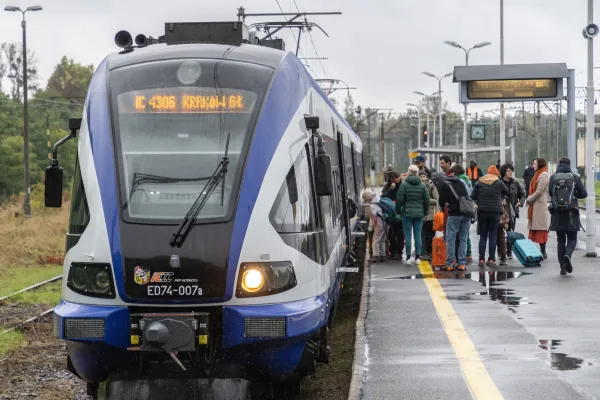 Na zdjęciu stojący ludzie 