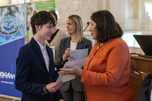 Na zdjęciu stojący ludzie 