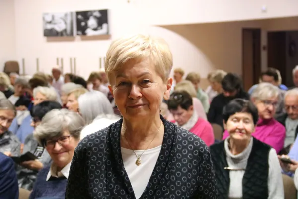 Na zdjęciu stojący ludzie 