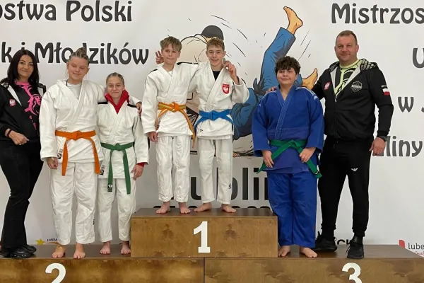 Na zdjęciu stojący ludzie 