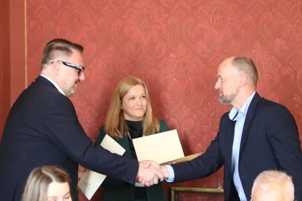 Na zdjęciu stojący ludzie 