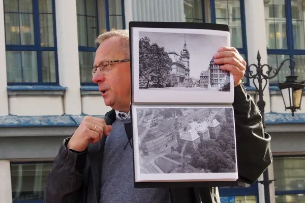 Na zdjęciu stojący ludzie 