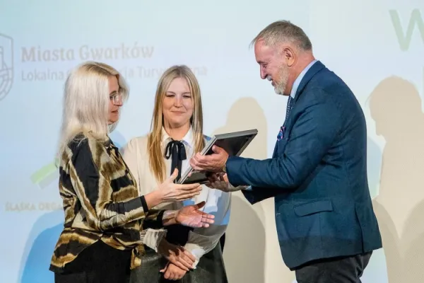 Na zdjęciu stojący ludzie 