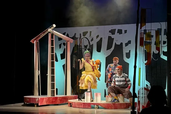 Na zdjęciu scena ze spektaklu - trzy postaci na tle scenografii