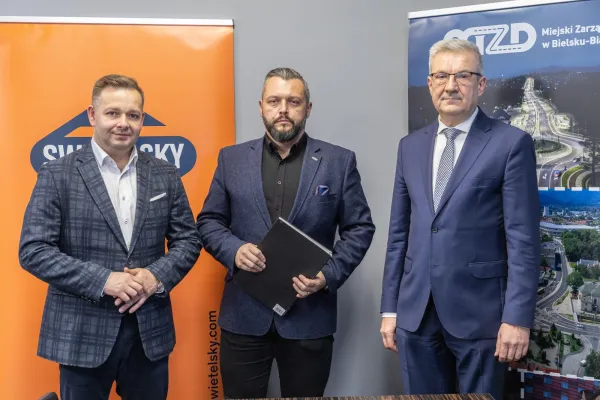 Na zdjęciu stojący ludzie 