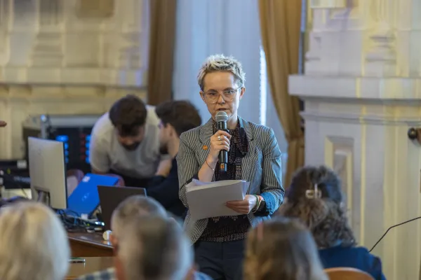 Na zdjęciu stojący ludzie 