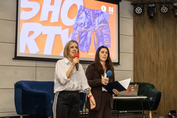 Na zdjęciu stojący ludzie 