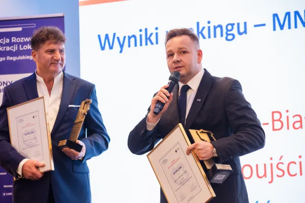 Na zdjęciu stojący ludzie 