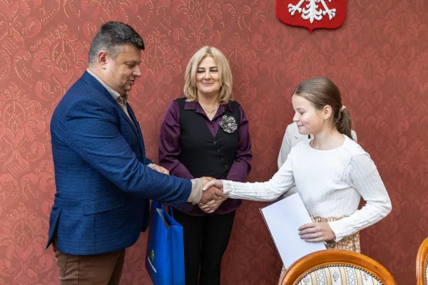 Na zdjęciu stojący ludzie 