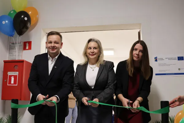 Na zdjęciu stojący ludzie 