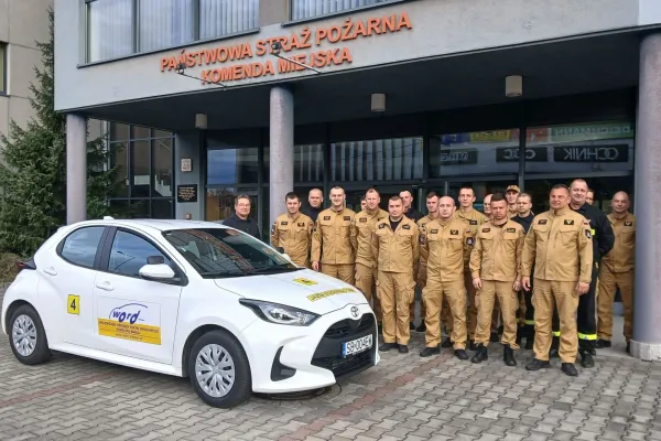 Na zdjęciu stojący ludzie 