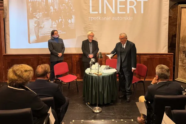 Na zdjęciu trzej panowie stoją, widoczne osoby na widowni