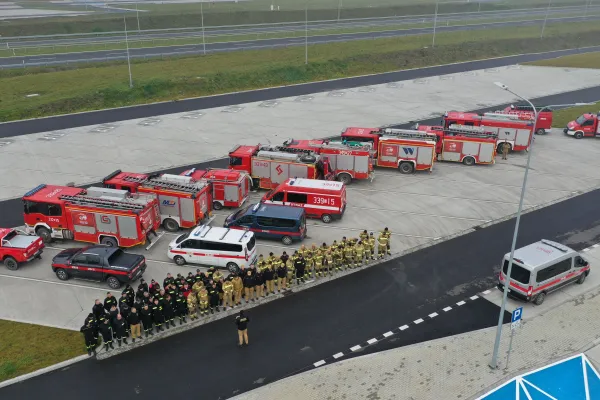 Na zdjęciu stojący ludzie 