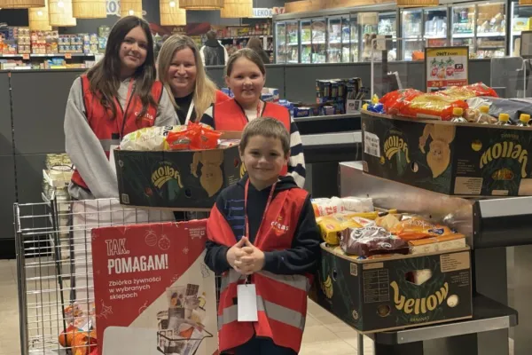 Na zdjęciu stojący ludzie 