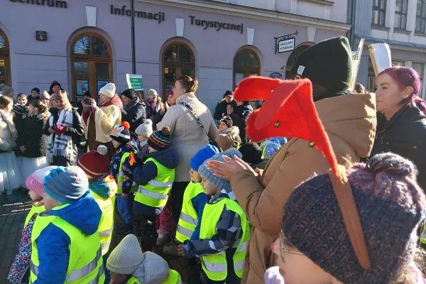Na zdjęciu stojący ludzie 