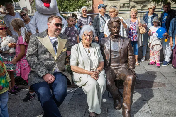 Na zdjęciu: mężczyzna, kobieta i rzeźba siedzący na ławce