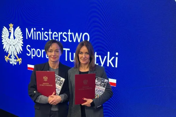 Na zdjęciu stojący ludzie 